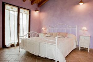 a bedroom with a white bed and purple walls at Agriturismo Il Colle del Falco in Borghetto