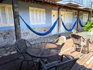 a patio with a table and chairs and a hammock at Flat e suítes com deque, cozinha e churrasqueira in Conservatória