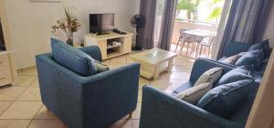 a living room with two blue chairs and a television at Residence les orchidees in Flic-en-Flac