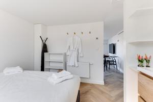 een witte slaapkamer met een bed en een eetkamer bij Vernieuwd Zeezicht Villa Duin Suite in Bergen aan Zee