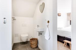 een witte badkamer met een toilet en een wastafel bij Vernieuwd Zeezicht Villa Duin Suite in Bergen aan Zee +28 foto's
