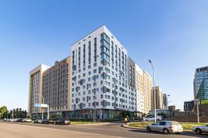 a tall white building on a city street with cars at Мангилик жилой комплекс in Astana