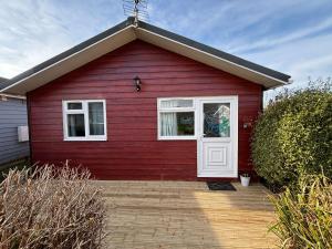 a red house with a white door at Trevone - Chalet 130 in Padstow