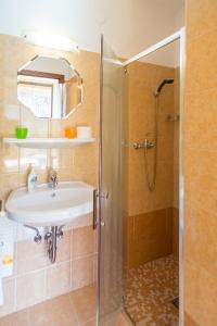 une salle de bain avec un lavabo et une douche dans l'établissement Andrea Apartmanház, à Balatongyörök