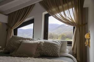 a bedroom with a large window with a view of mountains at El Nial del Gorrión - Las Casas del Oso in Toriezo