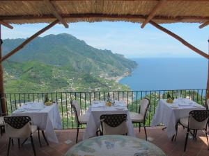 a restaurant with tables and chairs and a view of the ocean at Hotel Parsifal - Antico Convento del 1288 in Ravello