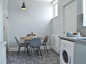 Una cocina con una mesa con sillas y una lavadora. en The Beach House, en Saint Annes on the Sea