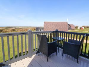 a patio with chairs and a table on a deck at Owls Nook in Bude +7 photos
