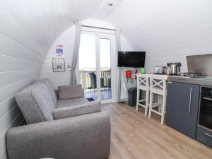 a living room with a couch and a kitchen at Owls Nook in Bude