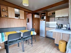 una pequeña cocina con mesa y sillas en una habitación en Le Ti Bois, Chalet tout équipé vue forêt, 5 prs, en La Teste-de-Buch