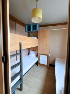 Una pequeña habitación con una litera y una escalera. en Le Ti Bois, Chalet tout équipé vue forêt, 5 prs, en La Teste-de-Buch