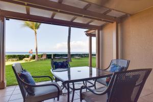 a table and chairs on a patio with a view of the ocean at Lahaina Condo with Patio, Ocean Views and Pool Access! in Kahana