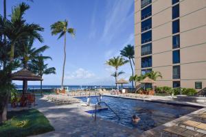a pool at a resort with palm trees and the ocean at Lahaina Condo with Patio, Ocean Views and Pool Access! in Kahana