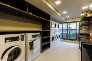 een wasruimte met 3 wasmachines en drogers bij 360 Soma Perdizes in Sao Paulo