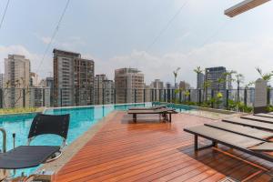 a rooftop deck with picnic tables and a city skyline at 360 Soma Perdizes in Sao Paulo