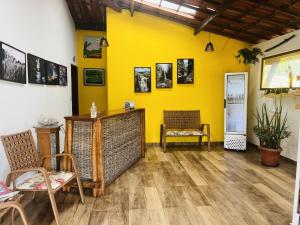 a room with a yellow wall with chairs and a table at Pousada Recanto da Chapada in Mucugê