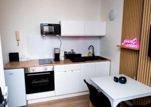 a small kitchen with white cabinets and a table at GOOD VIBES VILLEURBANNE - Proche GARE Part Dieu in Villeurbanne