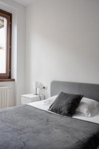 ein weißes Schlafzimmer mit einem Bett mit einem grauen Kissen in der Unterkunft Boutique House in corte storica in Seregno + 22 Fotos