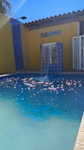 a swimming pool with a water fountain in a house at Casa De Praia Baptista Resort Jacaraípe in Serra