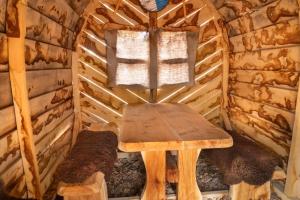 einen Holztisch in einer Blockhütte mit einem Fenster in der Unterkunft Suite WIDAR - Odins Blick Wohnung 2 - Privatstrand, Sauna, Garten in Lobbe
