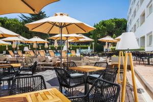 an outdoor patio with tables and chairs and umbrellas at The Patio Suite Hotel in Albufeira