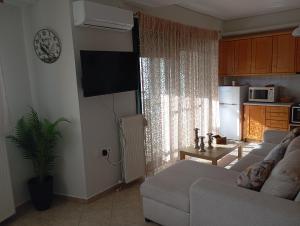 a living room with a couch and a tv and a kitchen at Volos Seaside Studio in Volos