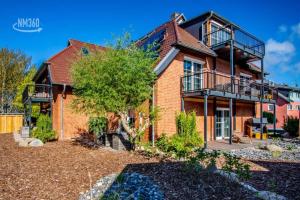 a large brick house with a balcony at Suite ODINS HALLE - Odins Blick Wohnung 8 - direkt am Privatstrand, Sauna, Garten in Lobbe