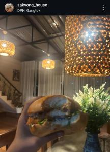 een persoon met een hamburger in zijn hand bij Sakyong house apartment in Gangtok