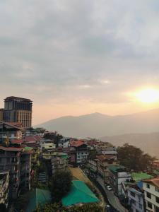 een uitzicht op een stad met ondergaande zon bij Sakyong house apartment in Gangtok