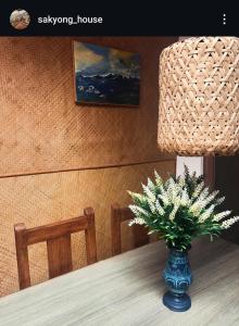 een vaas met bloemen op een tafel met een lamp bij Sakyong house apartment in Gangtok