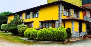 a yellow house with bushes in front of it at APARTAMENTOS MARIAJE in Barro de Llanes