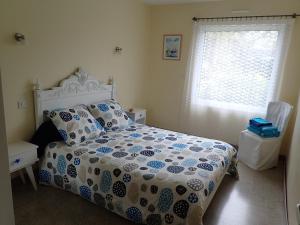 a bedroom with a bed with a blue and white comforter and a window at Holiday Home Lochrist Le Conquet in Le Conquet