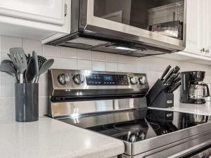 a kitchen with a stainless steel stove and a microwave at Coler Lounge Cyclist's Dream Home with Hot Tub in Bentonville +23 photos