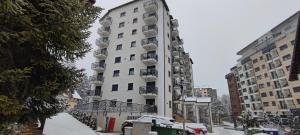 un edificio alto y blanco con nieve en el suelo en Planinski Biser - Spa & Lux Apartment, en Zlatibor