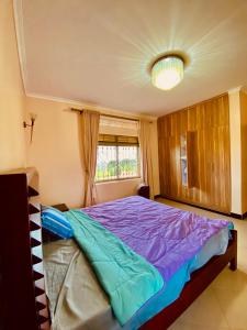 KyegegwaにあるKamu-Eco Safari Resortのベッドルーム1室(紫のシーツが敷かれたベッド1台、窓付)