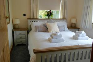 een slaapkamer met een wit bed en handdoeken bij Ashford House 2 bedroom Apartment 'outdoor bathing tub' in Fylingthorpe