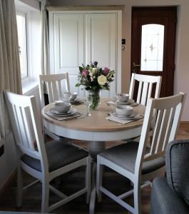 - une table à manger avec un vase de fleurs dans l'établissement Ashford House 2 bedroom Apartment 'outdoor bathing tub', à Fylingthorpe