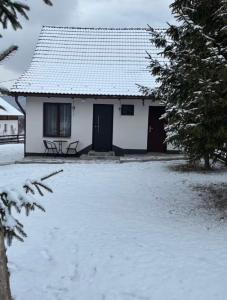 a white house with a bench in the snow at Margaréta kulcsosház in Sub Cetate