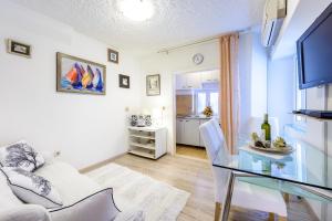 a living room with a glass table and a kitchen at Apartman Antonio in Dubrovnik