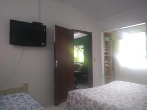 a bedroom with a bed and a television on the wall at Recanto da mata in Florianópolis