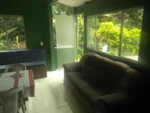 a living room with a couch and two windows at Recanto da mata in Florianópolis