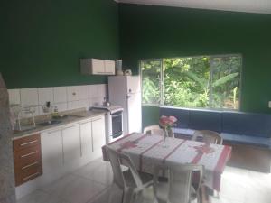 a green kitchen with a table and a window at Recanto da mata in Florianópolis