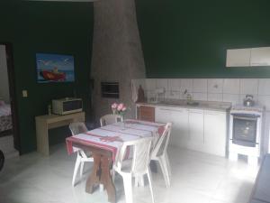 a kitchen with a table with white chairs and green walls at Recanto da mata in Florianópolis
