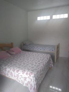 a bedroom with two beds and two windows at Recanto da mata in Florianópolis