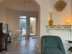 a living room with a green chair and a piano at Vakantiehuis 'Dune' de panne in De Panne