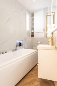a white bathroom with a tub and a sink at Appartement Raffiné avec Jacuzzi et AC - 6P in Paris