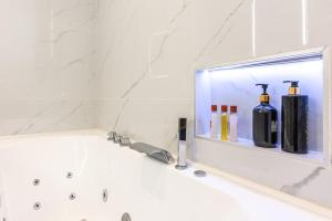 a bathroom with a bath tub with bottles on a shelf at Appartement Raffiné avec Jacuzzi et AC - 6P in Paris