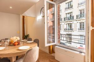 a dining room with a table and a large window at Appartement Raffiné avec Jacuzzi et AC - 6P in Paris
