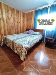 una camera da letto con un letto in una stanza con pareti in legno di Cabañas Dos Laureles a Coñaripe