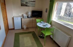eine kleine Küche mit einem kleinen Tisch und grünen Stühlen in der Unterkunft Pendine Sands Guest House in Pendine